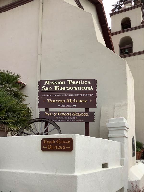 Post and panel signs made of wood add to the historical charm of the San Buenaventura Mission.